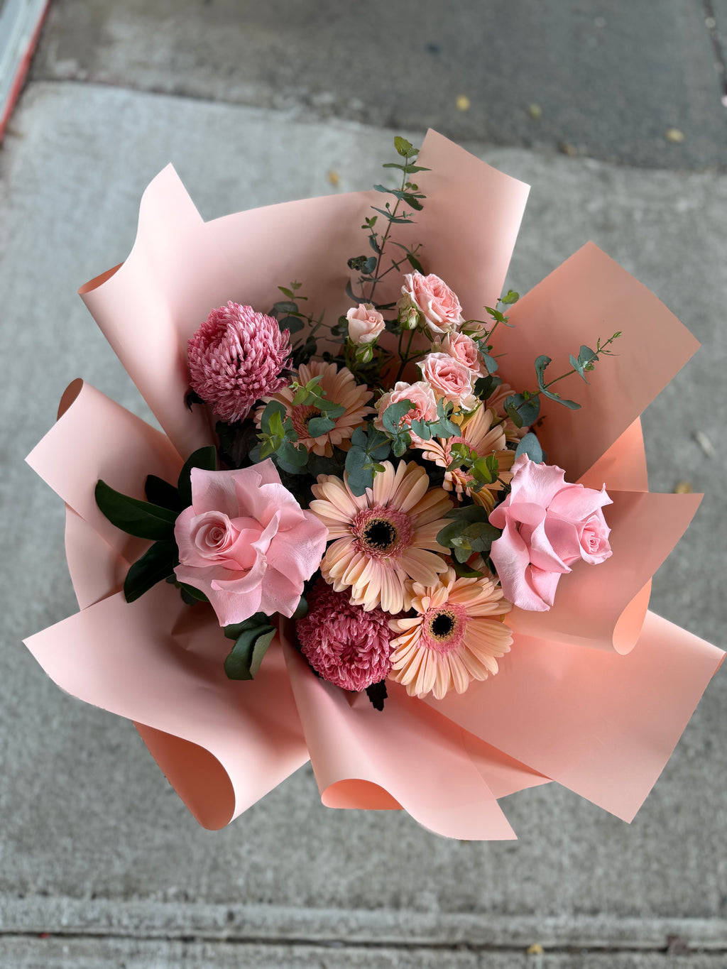 Bouquet of flowers wrapped in pink paper on a concrete surface