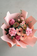 Bouquet of flowers wrapped in pink paper on a concrete surface