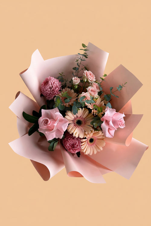 Bouquet of flowers wrapped in pink paper on a concrete surface